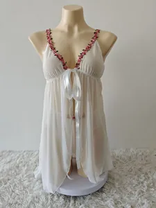 Détail de la nuisette blanche transparente avec broderie florale et nœud en satin