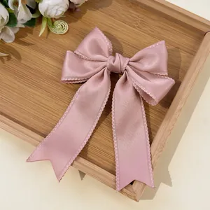 Detailed macro view of pink satin bow hair clip with intricate scalloped lace edges
