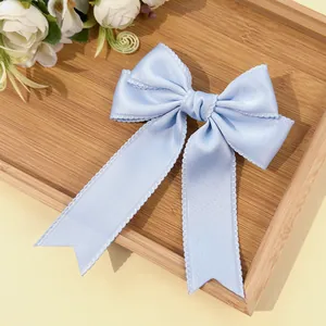 Detail of light blue satin hair bow clip with elegant ruffled lace edges and long ribbons