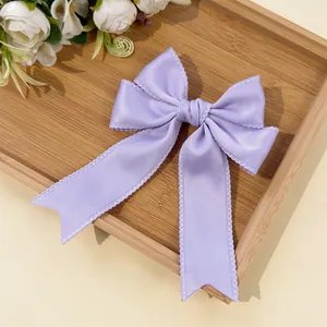 Close-up of a lavender bow hair clip with lace edges on a wooden tray for styling