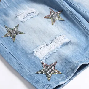 Détail d'un short en jean déchiré bleu clair avec écussons étoiles brodées en strass
