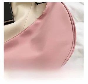 Detail view of pink nylon dumpling bag showing fine stitching and smooth fabric texture