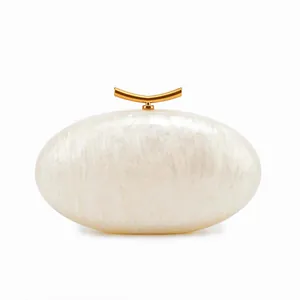 Detail of white acrylic shell evening clutch with elegant golden metal clasp closure