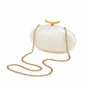 Detail of elegant white pearlescent acrylic shell clutch with gold chain strap