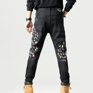 Slim fit zwarte herenspijkerbroek met kleurrijke verfspatten op de achterkant van