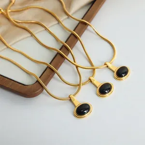 Detail view of retro gold snake chains with oval black gemstone pendants on silk