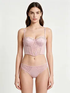 Detailed close-up of light pink lace corset bra and matching satin floral panties set