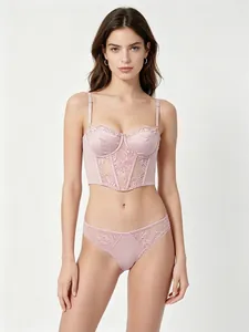 Detail of pale pink corset-style lingerie set with floral lace and satin finish