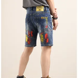 Men's denim shorts in mid-wash blue with artistic red and yellow paint splatter design