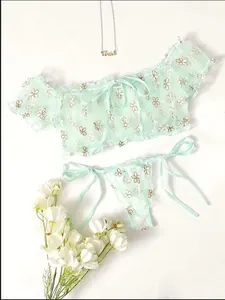 Detail of mint green lace lingerie set with white floral embroidery and bow details