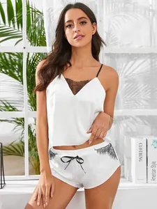 Detailopname van wit satijnen hemdje met zwart kant en strikjes bij de korte broek