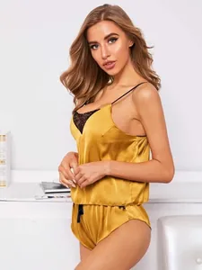 Detail van gele satijnen lingerieset met zwart kant aan de camisole en de shorts