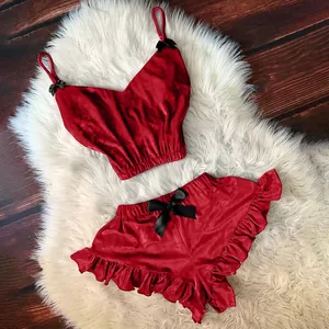 Completo intimo in velluto rosso con pizzo e fiocchi neri su tappeto di pelliccia sintetica
