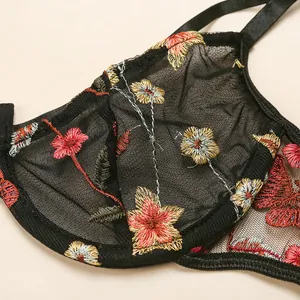 Detailed close-up of intricate multi-color floral embroidery on black mesh lace lingerie