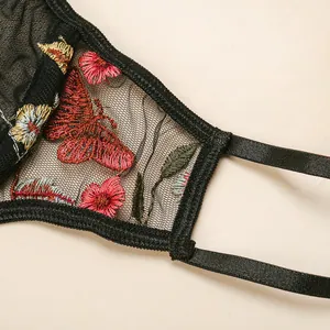 Detailed view of black mesh lingerie featuring colorful floral and butterfly embroidery
