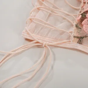Detail mit rosa Blumenstickerei und transparentem Netzgewebe mit Schnürbändern