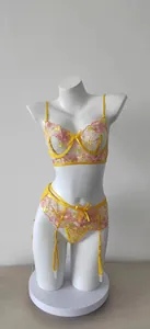 Close-up of yellow sheer mesh lingerie set with vibrant floral embroidery and garter details