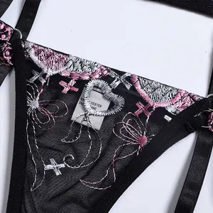 Détail d'un string en dentelle avec broderie florale rose et patch en forme de cœur