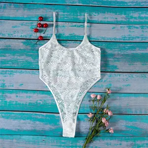 Flat lay of a white floral lace bodysuit with spaghetti straps on a rustic wood floor