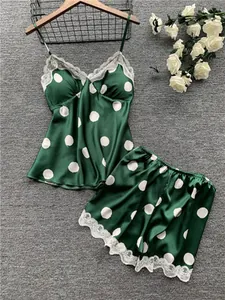 Flat lay of retro dark green satin pajama set with white polka dots and lace trim detail