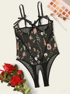 Detailed macro view of black sheer bodysuit featuring floral embroidery and ribbon accents