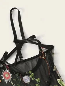Detailed close-up of floral embroidery and satin bow on black sheer mesh lingerie top