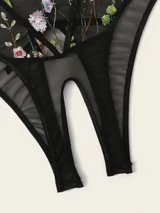 Detailed close-up of sheer black mesh lingerie with colorful floral embroidery and cut-out