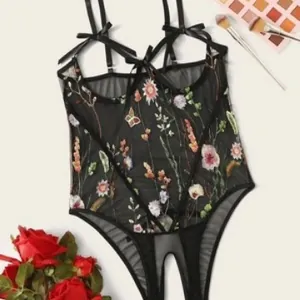 Black sheer mesh bodysuit featuring colorful floral embroidery and satin bow straps