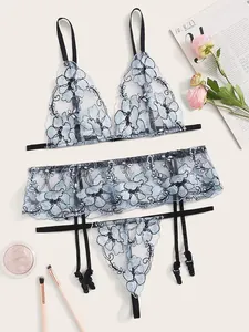 Detail view of light blue mesh lingerie with delicate floral embroidery and ruffled trim