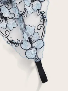 Close-up of white sheer mesh fabric with blue floral embroidery and black trim details