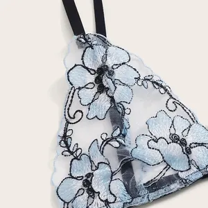 Detailed view of light blue lace embroidery on sheer mesh lingerie with black straps