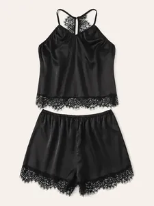 Flat lay of black satin sleepwear set featuring delicate lace trim on camisole and shorts