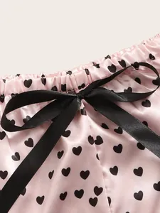 Nahaufnahme von rosa Satin-Pyjama-Shorts mit schwarzen Herzprints und einer Schleife