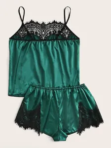 Detail of dark green satin sleepwear with intricate black lace trim and silk texture