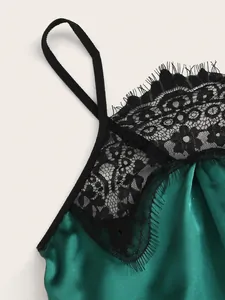 Detail of dark green satin chemise featuring delicate black floral lace and eyelash trim