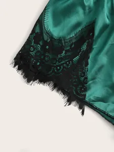 Detailed macro view of emerald green satin sleepwear with delicate black eyelash lace trim