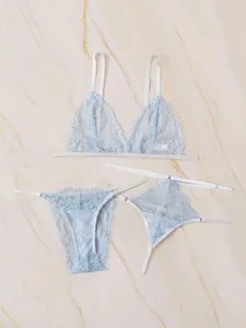 Flat lay of light blue three-piece lace lingerie set with floral embroidery and eyelash trim