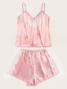 Detail van roze satijnen hemdset met witte wimperkant en elastische korte broek voor dames