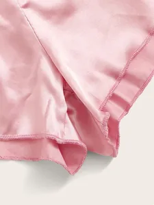 Detailopname van de lichtroze satijnen shorts met gladde textuur en fijne overlockstiksels