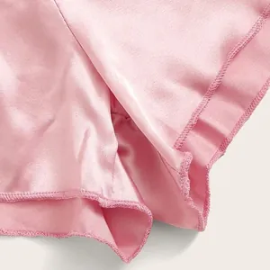 Detailopname van roze satijnen lingerieset met gladde stof en fijne stikdetails