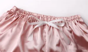 Dettaglio degli shorts da notte in raso rosa con fiocco bianco e elastico