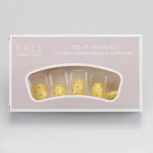Detail showing lemon yellow press-on nails with blue polka dots in retail packaging