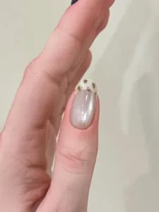 Macro shot of silver cat-eye press-on nails with cow print tips and sparkling metallic finish