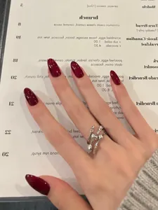 Detailed view of an almond burgundy press-on nail paired with a silver vine ring design