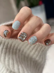 Detail of short punk style press-on nails with blue and brown star pattern designs