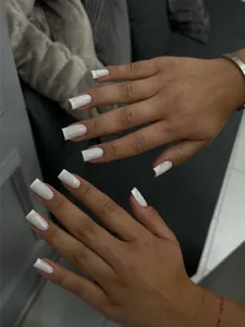 Detailed view of square white French press-on nails on hands with a minimalist finish