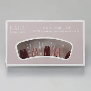 Detail of short burgundy and pink press-on nails with glitter and polka dot patterns
