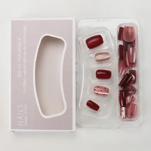 Detail of short burgundy and pink press-on nails with glitter and polka dots in packaging