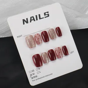 Burgundy and nude press-on nails with glitter and polka dots on a display card