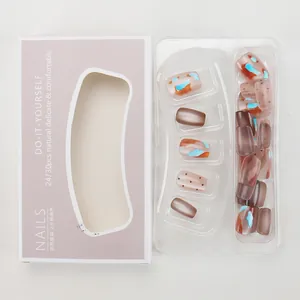 Detalle de uñas postizas ámbar con patrones de puntos en su caja de empaque